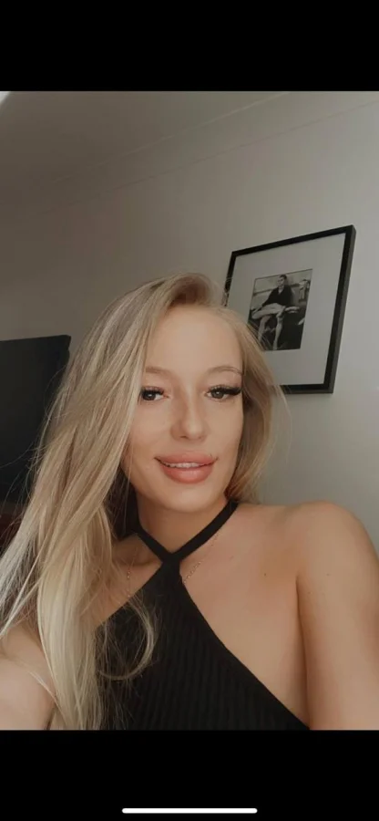 A blonde escorts selfie of her in a black top 