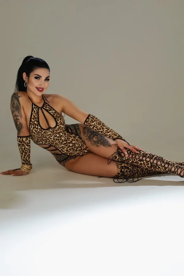 A sexy London escort laying on the floor wearing a leopard print body and sexy thigh high boots 