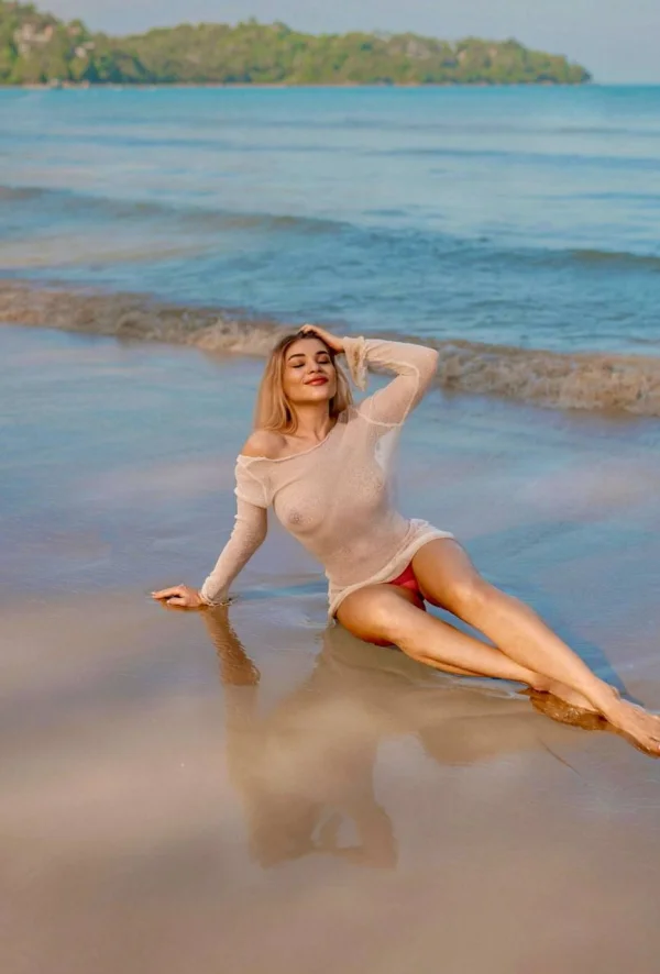 Sexy blonde lady laying on a beach wearing a see through top 