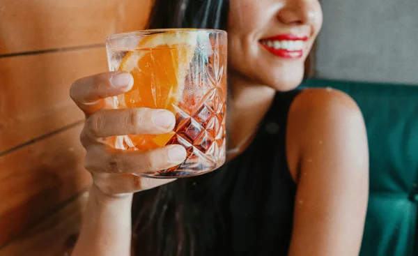 an escort in a black dress holding a cocktail