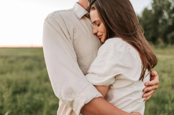 a woman hugging a man in a field