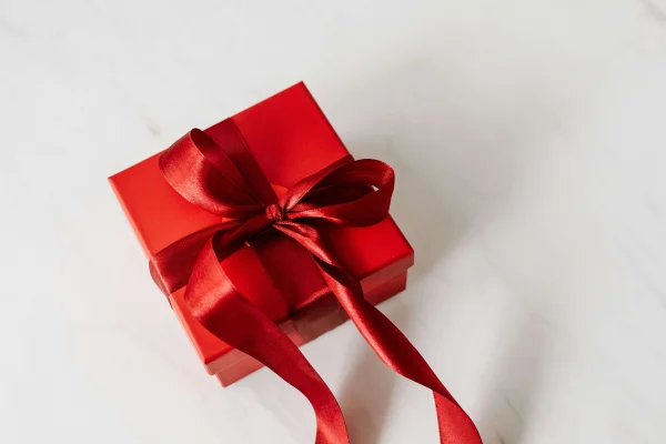 a red gift wrapped in a ribbon tied in a bow