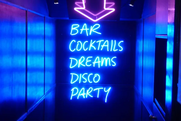 a neon sign leading to a party in a London nightclub