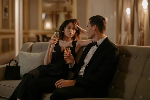 a woman and a man on a sofa drinking champagne