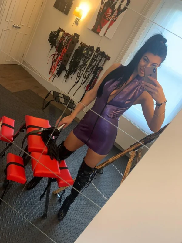 Mistress Devon taking a selfie wearing a purple latex dress
