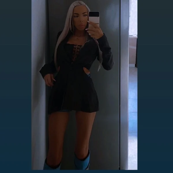 Busty slim blonde London escort pictured wearing a black dress 