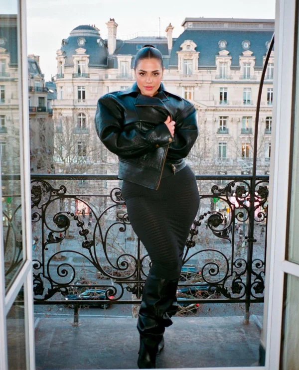 Curvy lady wearing a black leather jacket standing on a balcony 