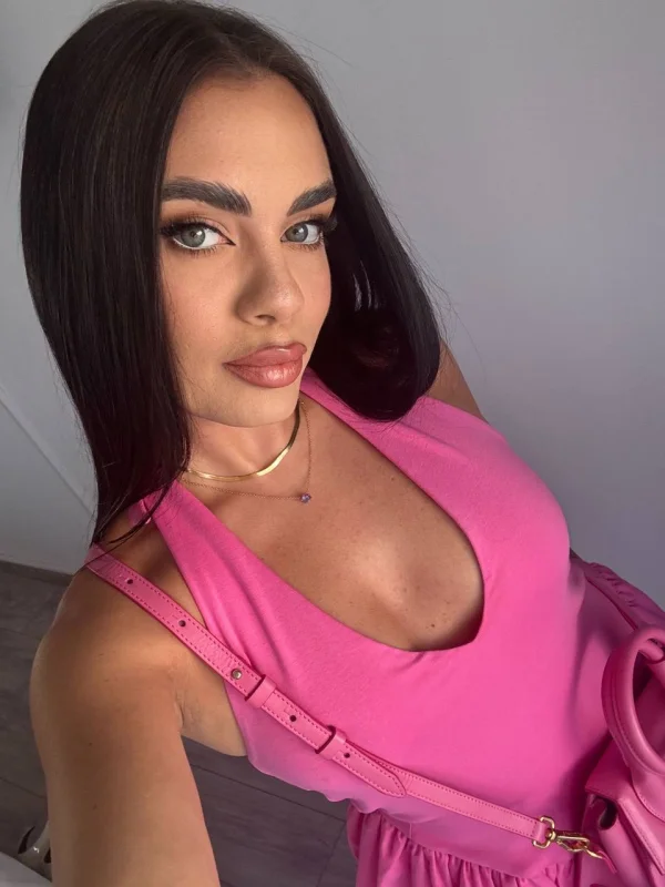 Brunette lady wearing a low cut pink dress 