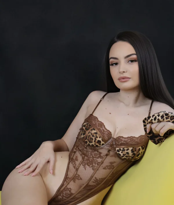 Slim beautiful brunette escort Janey laying on a sofa 
