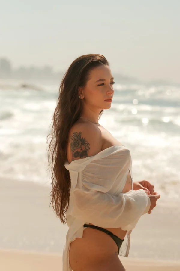 A lady wearing a white shirt that is drapped over her shoulders 