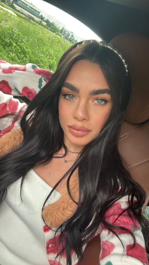 A very pretty brunette lady taking a selfie in a car 