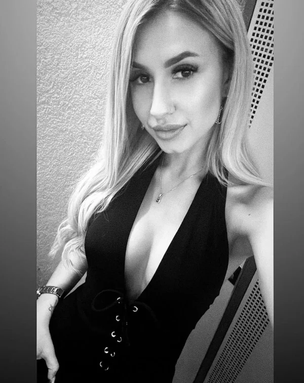 Black and white selfie of Giulia wearing a low cut black dress 