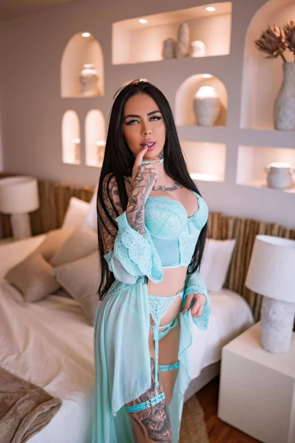 A lady standing by a sofa sucking her finger like it was a cock 