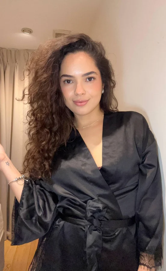A young lady with curly hair wearing a black satin robe 