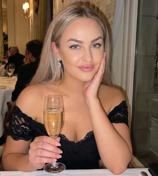 Alenka is sat at a table in a restaurant drinking a glass of wine 