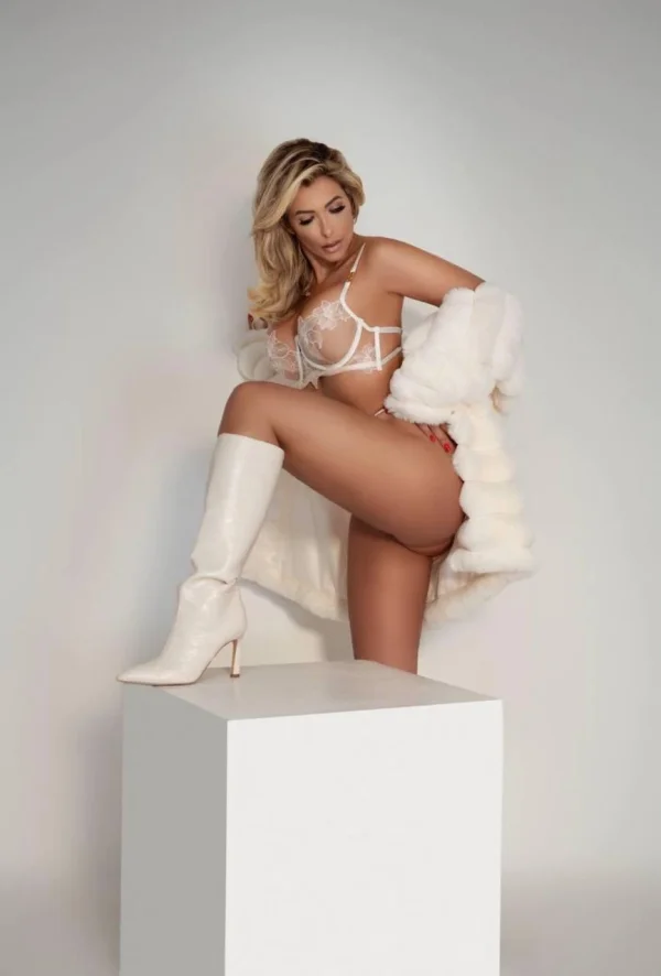 Elegant studio portrait of Munik in white designer lingerie and knee-high boots
