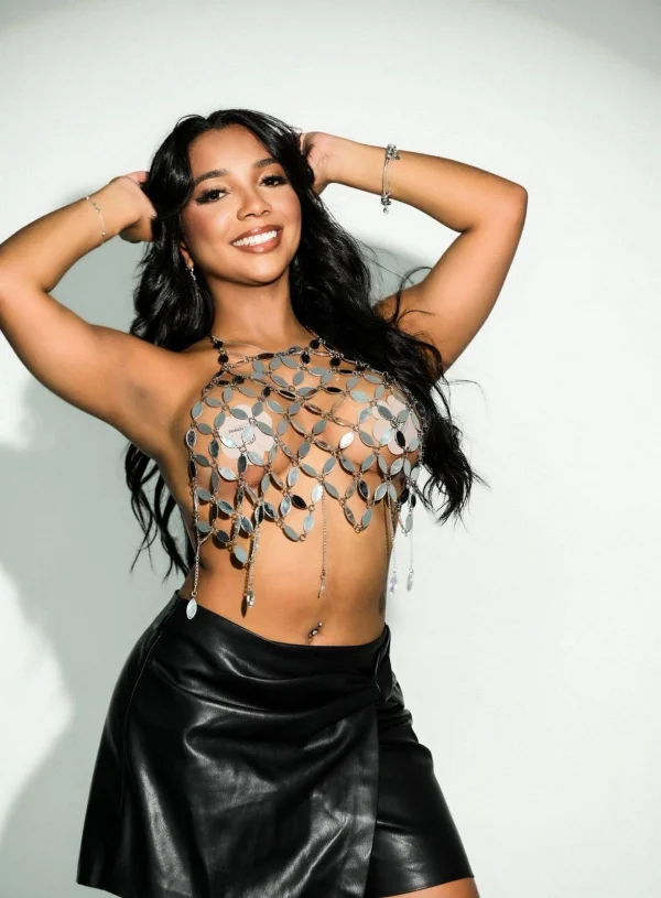 Jessamine posing confidently in a metallic chain top and leather mini skirt
