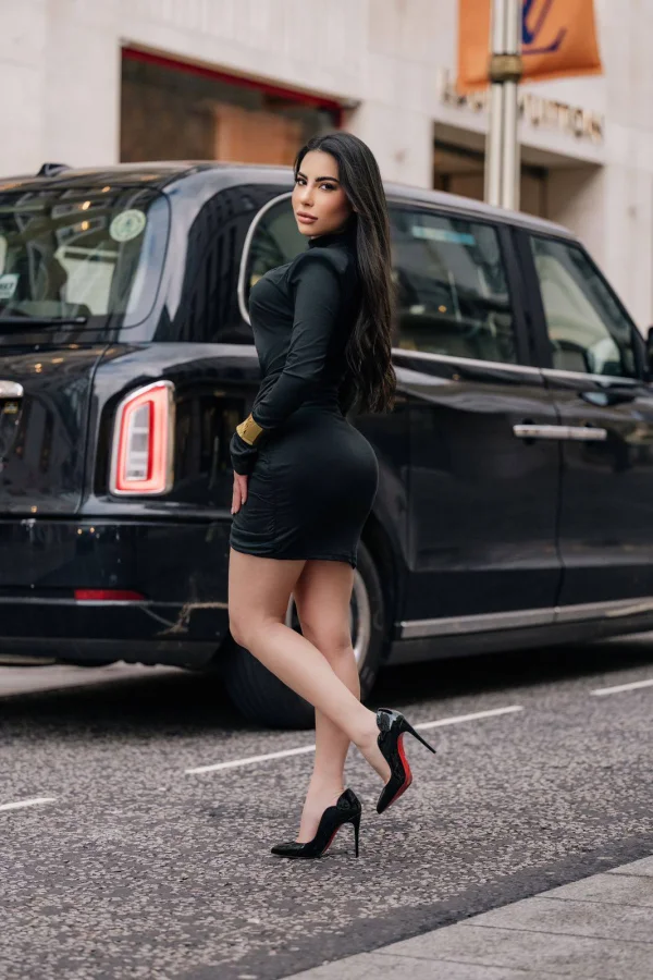 Mary Bell Brazilian escort posing beside a classic London black cab