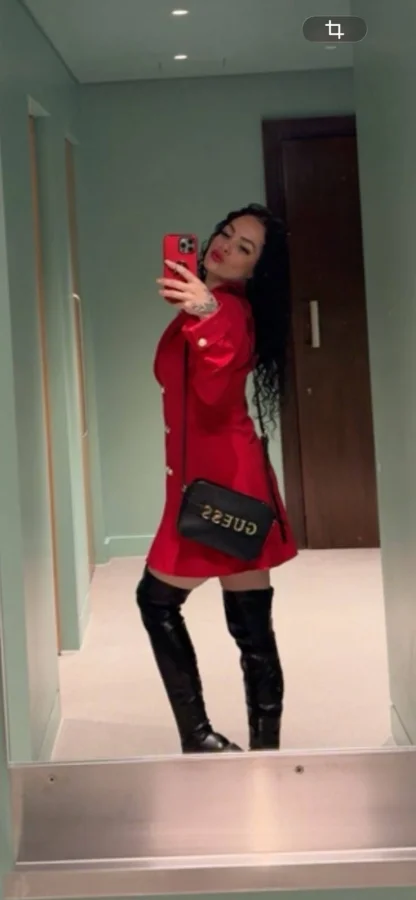 Mella wearing a red blazer dress with black thigh-high boots