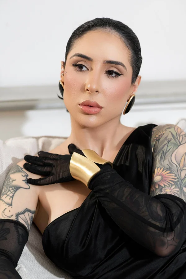 Nay wearing gold cuff bracelets and black eveningwear in a close-up portrait