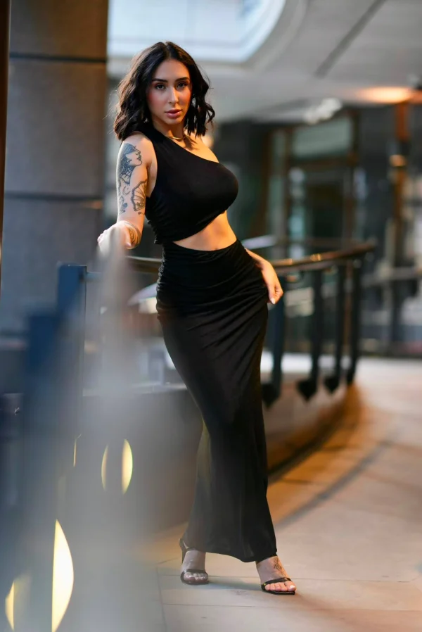 Nay posing in a black evening dress beside a railing